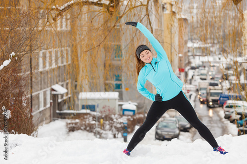Winter workout. Girl wearing sportswear, stretching exercises.