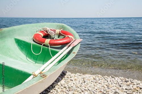 Old green paddle lifeboat on a pebble beach