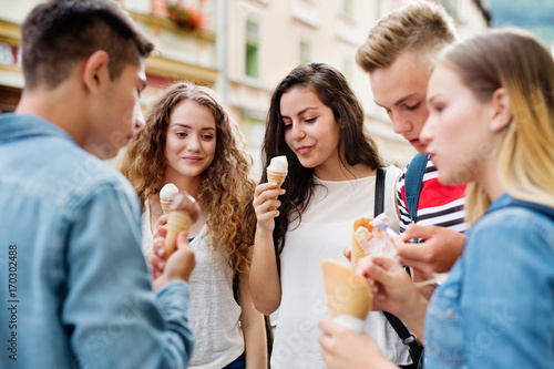 Attractive teenage students in town eating ice cream.