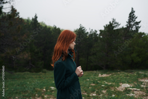 red-haired woman holding a camera in the forest