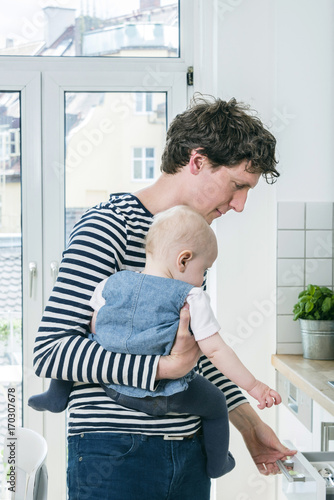 Father tending baby in kitchen