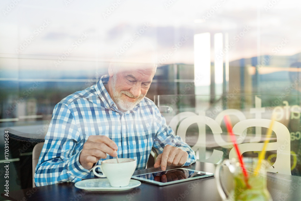 Senior businessman working on tablet in cafe Senior businessman working on tablet in cafe