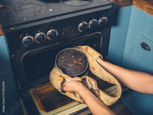 Man removing burnt cake from the oven