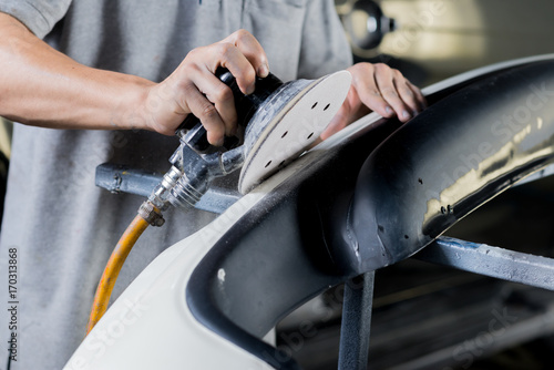 Schilderij op canvas Auto body repair series: Closeup of mechanic sanding car bumper