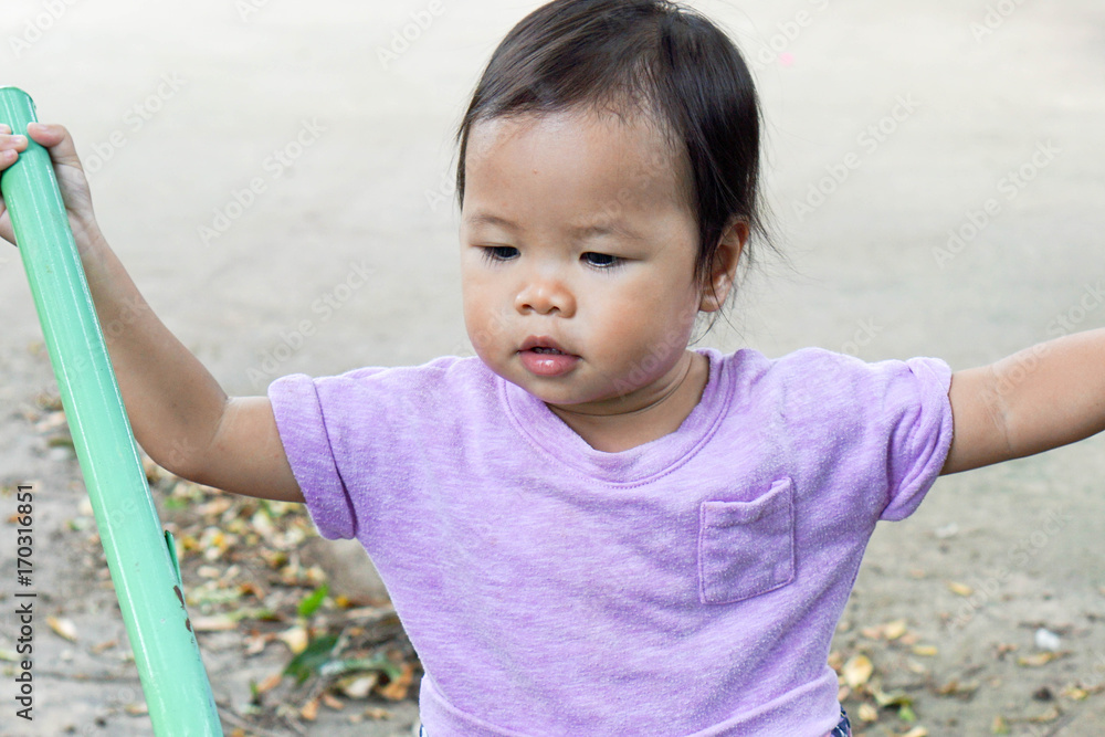 Toddler asian girl helping to clean up the leaves which pushing the wheelbarrow Toddler asian girl helping to clean up the leaves which pushing the wheelbarrow