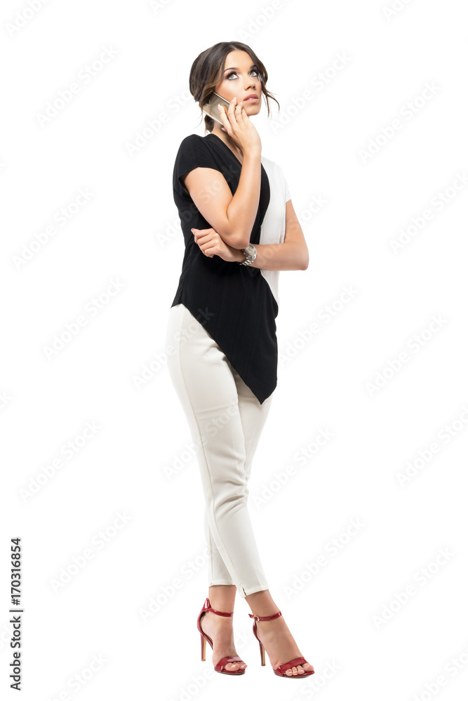 Worried young business woman in stylish suit talking on the mobile phone looking up. Full body length portrait isolated on white studio background Worried young business woman in stylish suit talking on the mobile phone looking up. Full body length portrait isolated on white studio background