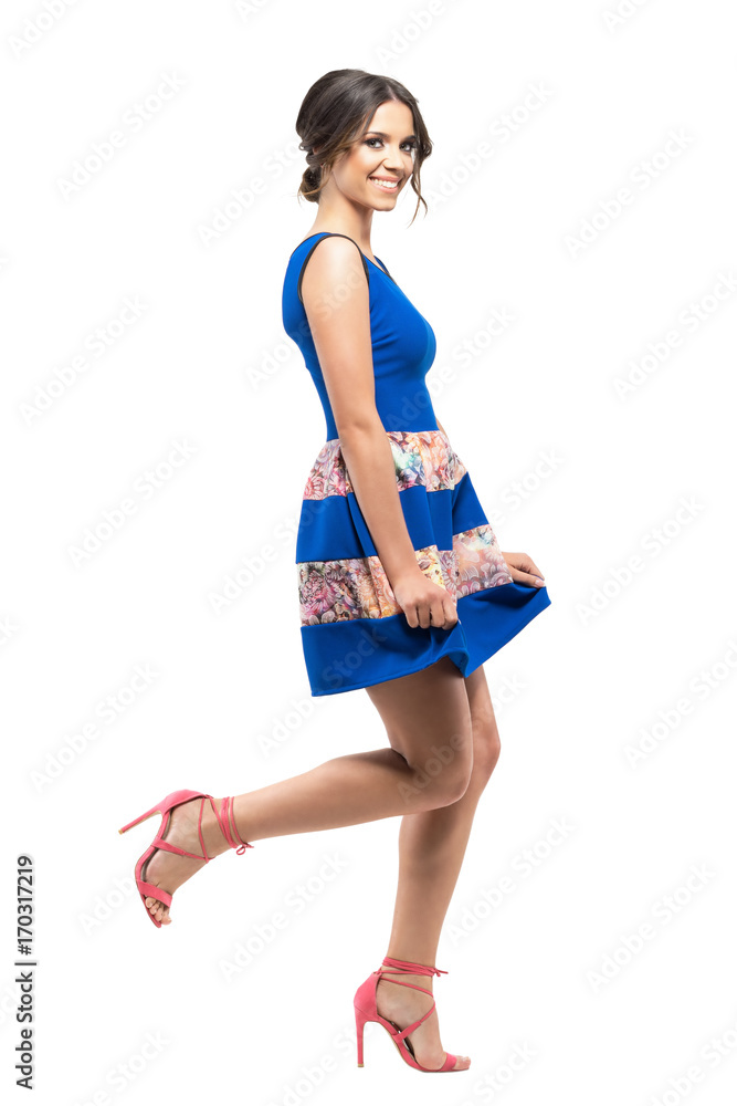 Cute charming girl in blue floral summer short dress bowing and smiling at camera. Full body length portrait isolated on white studio background Cute charming girl in blue floral summer short dress bowing and smiling at camera. Full body length portrait isolated on white studio background