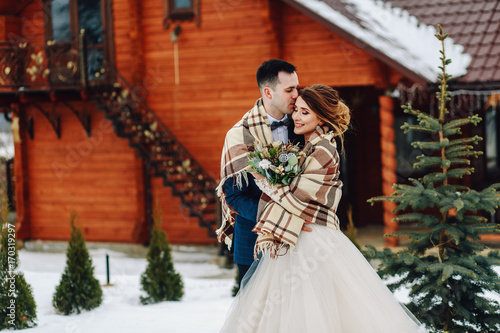 Winter wedding outdoors on background of snow-covered house.