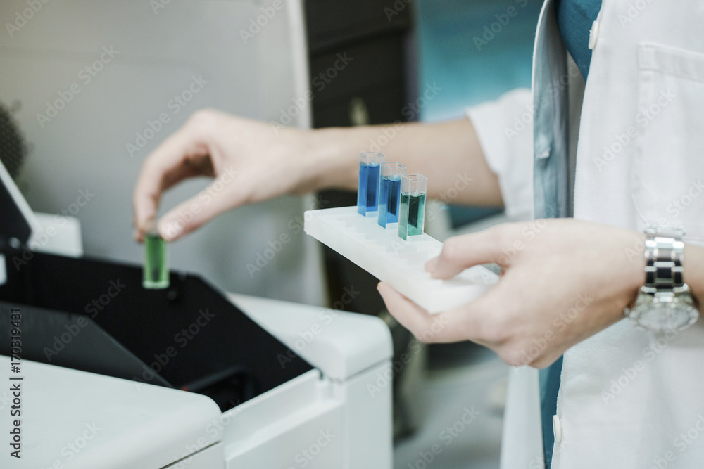 Scientist putting test tubes into scientific apparatus Scientist putting test tubes into scientific apparatus