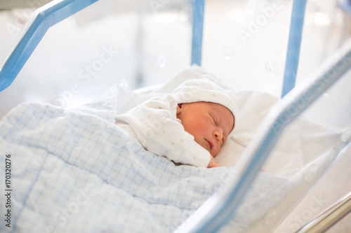 Newborn baby laying in crib in prenatal hospital photo