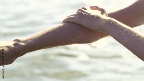 Beauty girl applying sunscreen suntan lotion from the bottle for body on the beach.