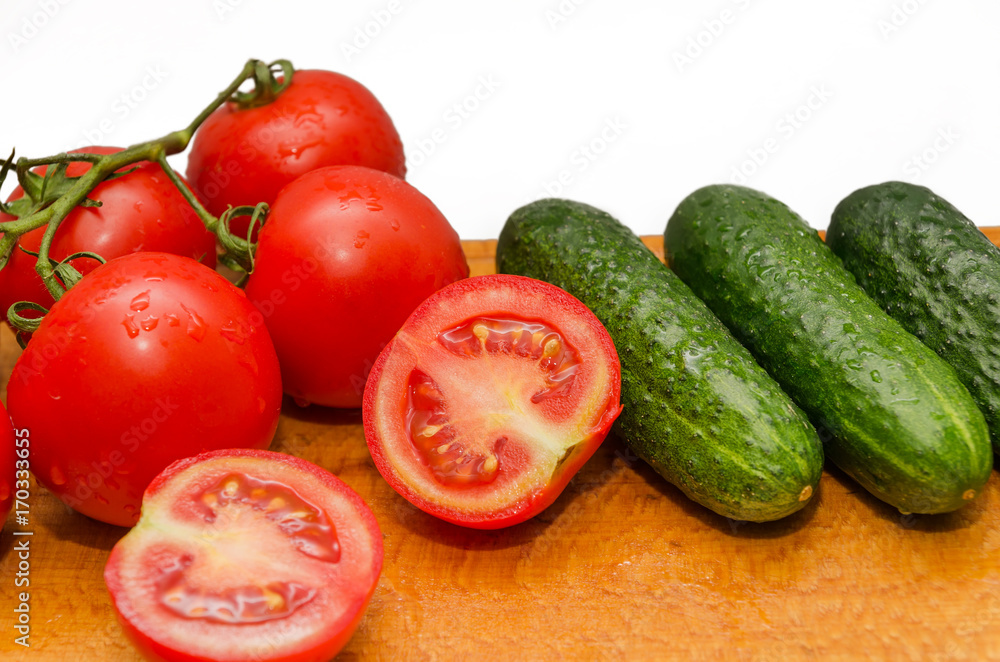 red tomatoes and green cucumber on board. white background red tomatoes and green cucumber on board. white background
