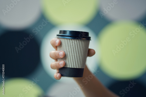 female hand holds a cup of coffee on a background of colored circles photo