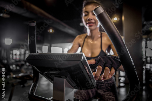 Healthy Asian women are electronic cycling for exercise in the gym. Shallow depth of field. Focus her hand.