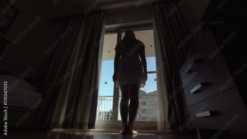 Back view of woman coming to window and opening curtains. Back view of woman coming to window and opening curtains.