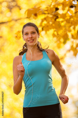 Young brunette woman running in autumn forest