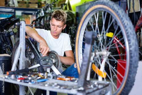 Man repairing bicycles with instruments indoors