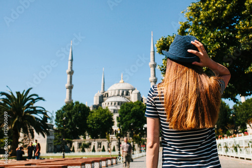 Photography A young girl traveler in a hat from the back in Sultanahmet Square next to the famous mosque called the Blue Mosque in Istanbul, Turkey