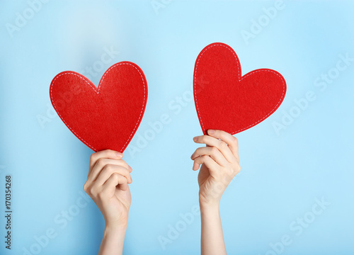 Woman holding red hearts on color background. Volunteer concept