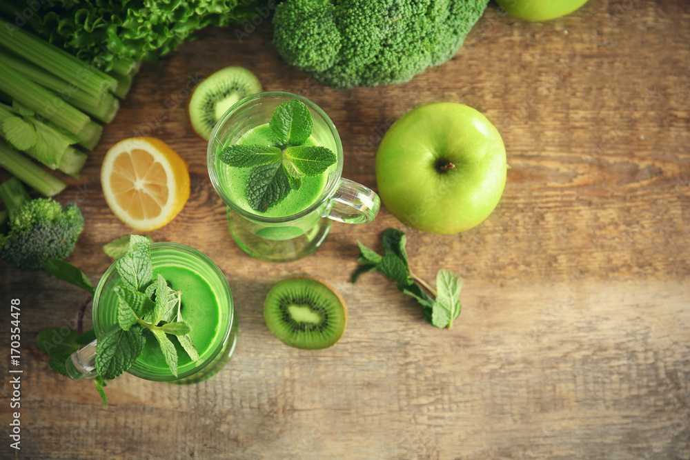 Fototapeta Glasses of green healthy juice with vegetables and fruits on wooden table