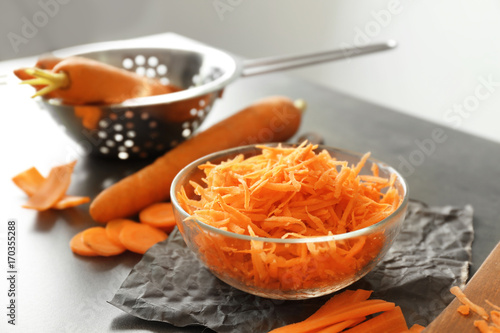 Glass bowl with grated carrot on kitchen table