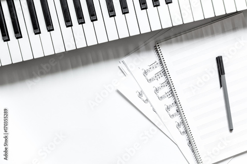 notebook with synthesizer in music studio for dj or musician work white desk background top view mock-up