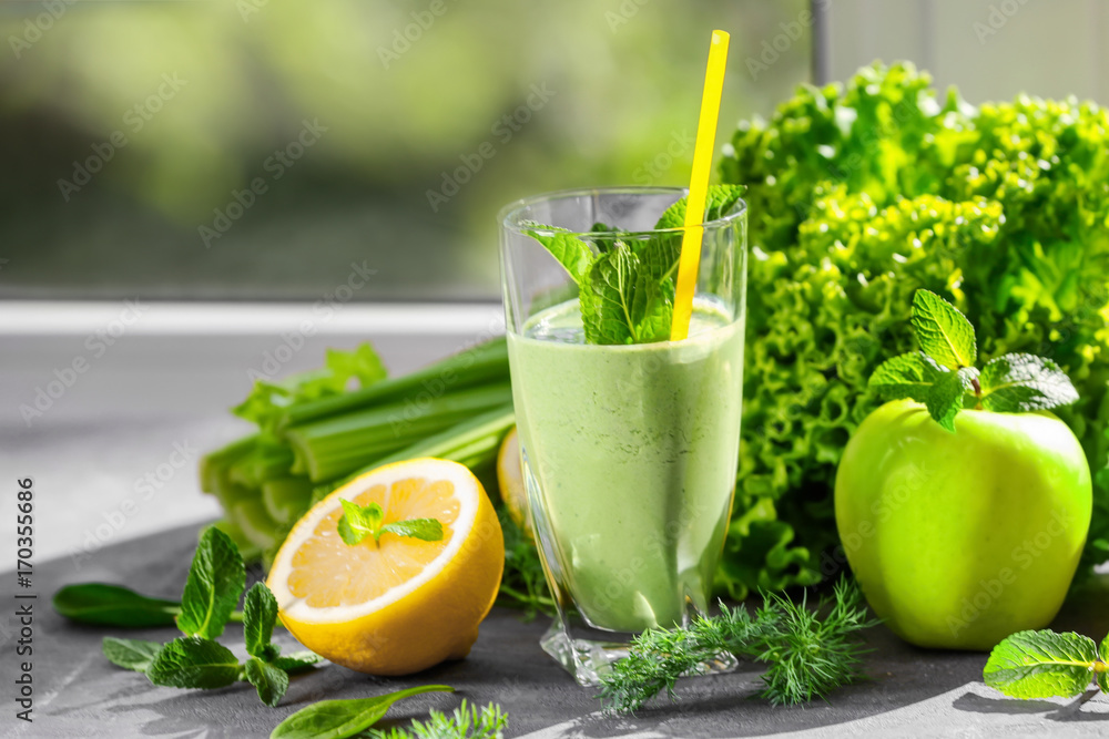 Glass of green healthy juice with fruits and vegetables on table Glass of green healthy juice with fruits and vegetables on table
