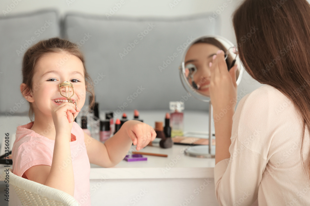 Young woman and her little daughter doing makeup at home Young woman and her little daughter doing makeup at home