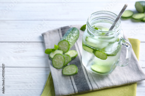 Delicious refreshing water with mint and cucumber in mason jar on table