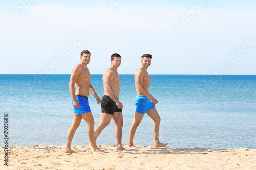 Handsome young men walking on sea beach
