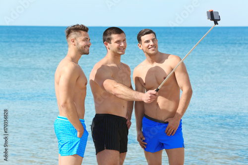 Handsome young men taking selfie on sea beach
