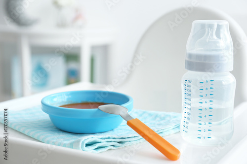 Baby bottle and bowl with puree on tray of highchair