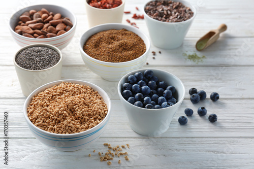 Composition with assortment of superfood products in bowls on light wooden background