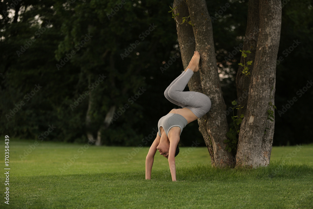 Young woman practicing yoga in park near trees Young woman practicing yoga in park near trees