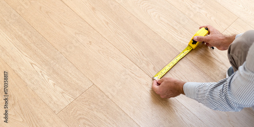 Architect taking measures of the new hardwood floor. Home and maintenance concepts