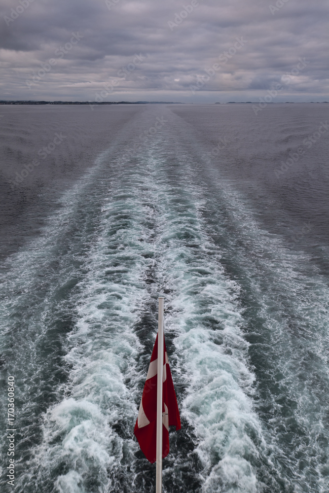 Fototapeta premium view from a ferry to a Norwegian flag and the suction of a ship's screw