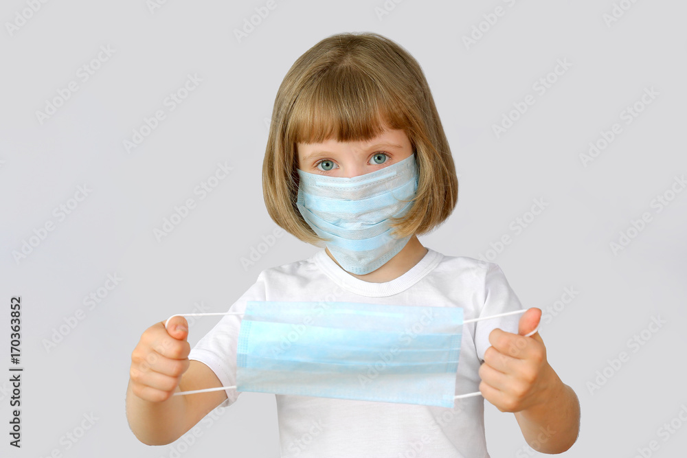 Child offers a medical mask.The child's portrait on a light background.