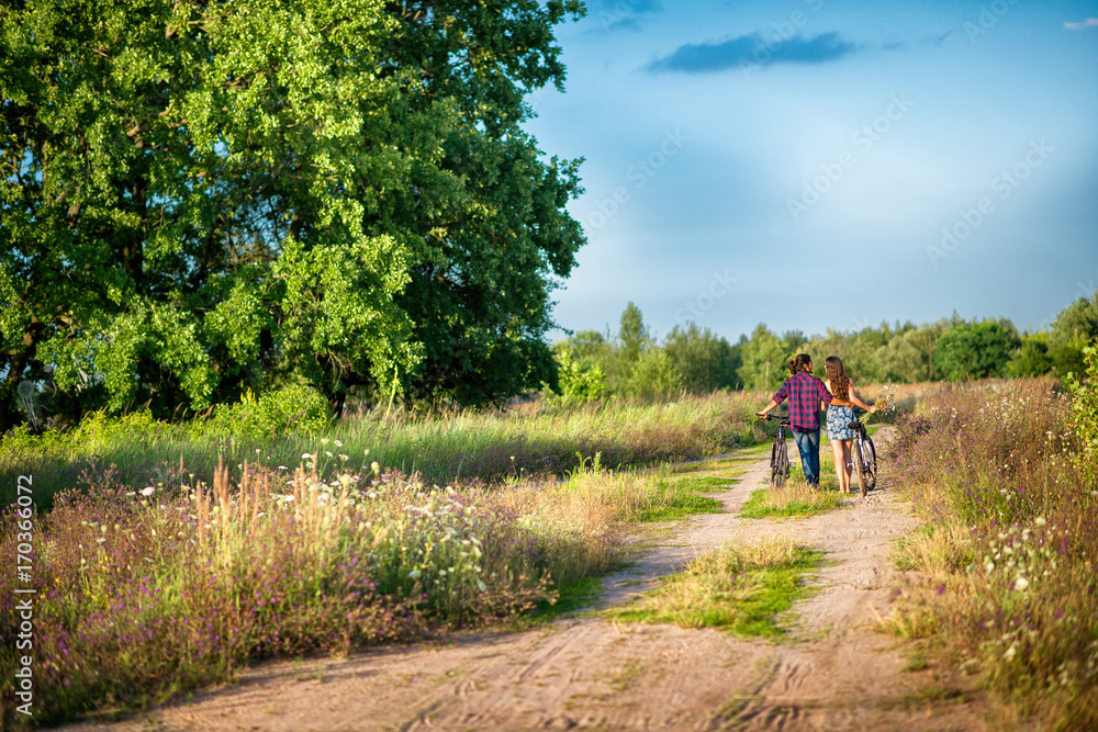 couple riding bikes in the hands of a girl a bouquet of wildflowers