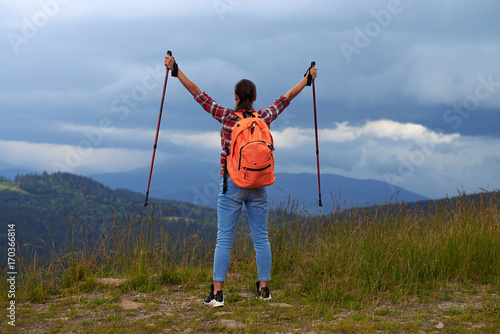 Young female with hiking poles outstretched hands