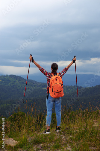 Young female hiker with poles outstretched hands