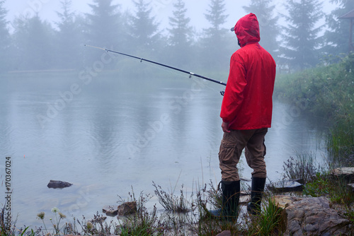 Man in waterproof jacket fishing on lake