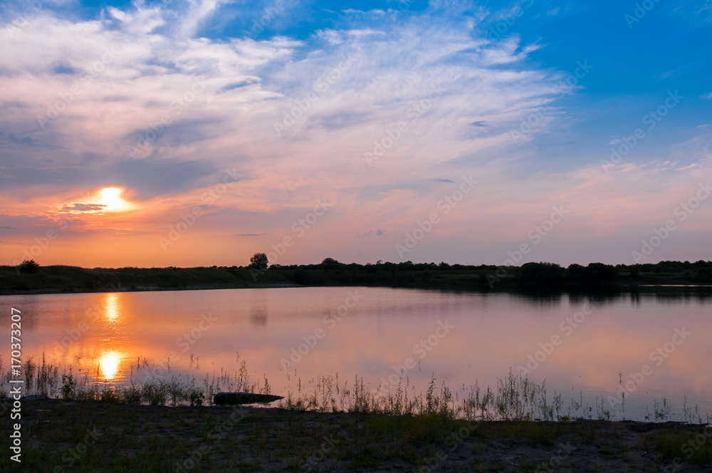 Summer landscape: the setting sun over the lake