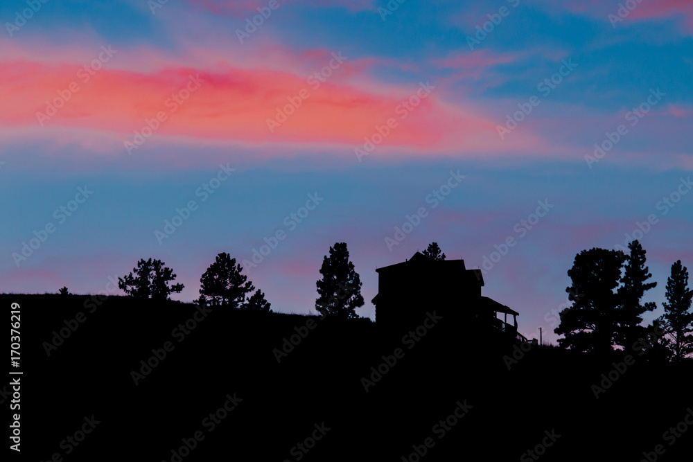 Fototapeta premium Beautiful sunset behind pine tree and house.
