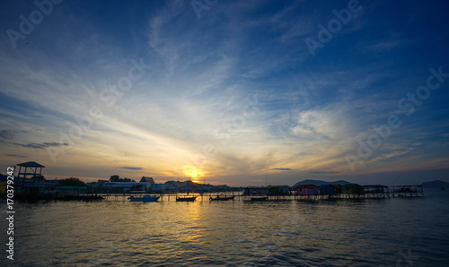 Beautiful sunrise view with background of boat, bungalow and a small island (Focus of sky) © Thammasiri
