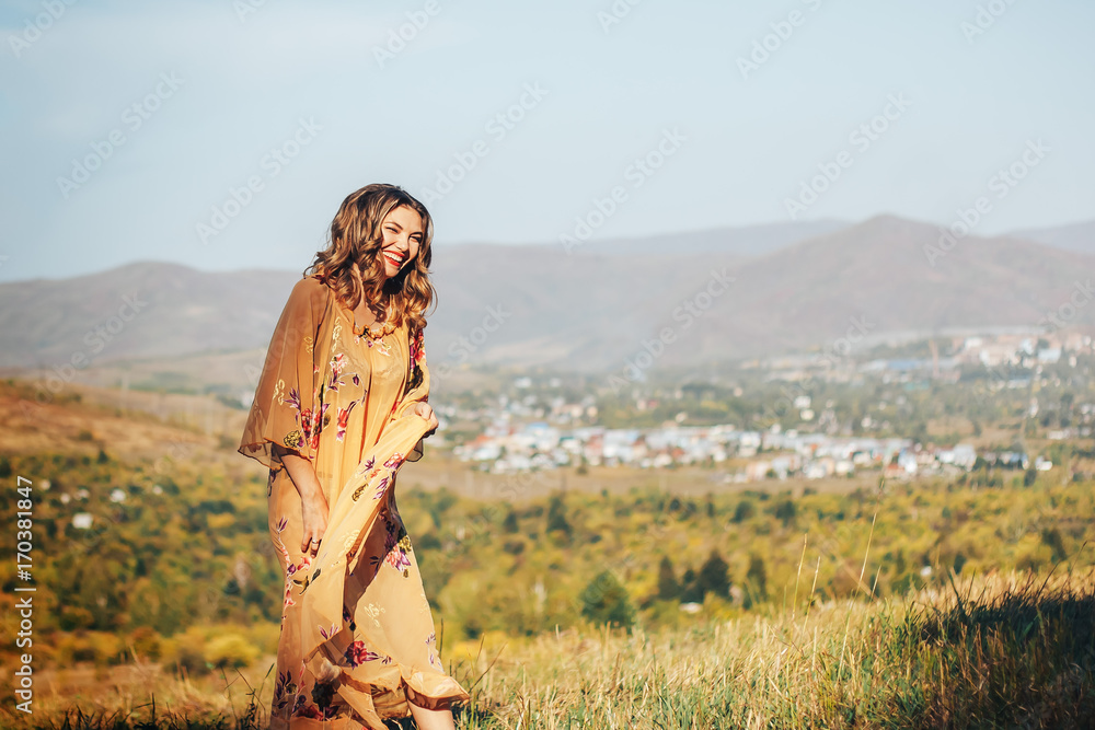 dancing laughing woman in yellow dress on field on city or country background