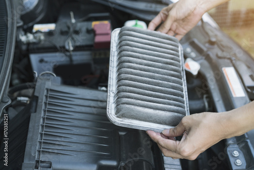 Technician holding dirty air filter for car, maintenance and repair concept