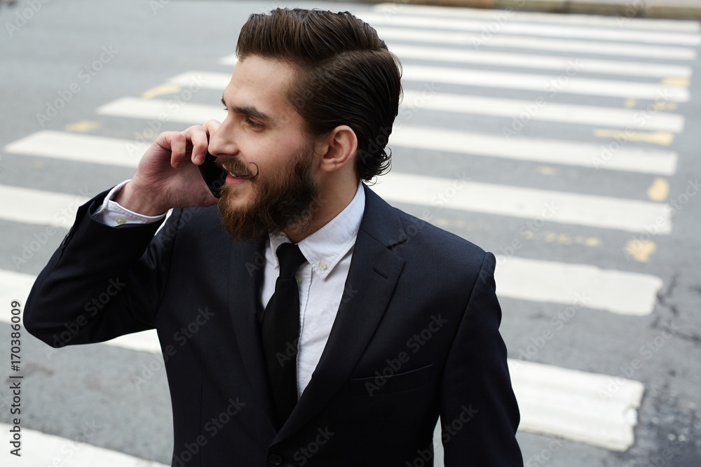 Young busy man with smartphone speaking while crossing street Young busy man with smartphone speaking while crossing street