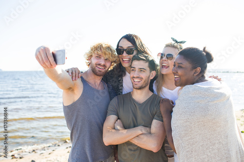 Friendly girls and guys making selfie on seashore during travel © pressmaster