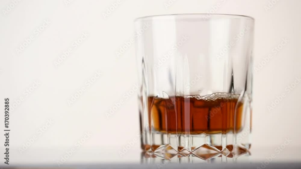 Faceted glass filled with whiskey and ice cubes Faceted glass filled with whiskey and ice cubes