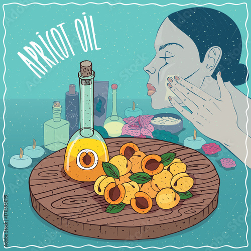 Glass Decanter of Apricot oil and fruits and kernel seeds of Prunus armeniaca plant. Girl applying facial mask on face. Natural vegetable oil used for skin care